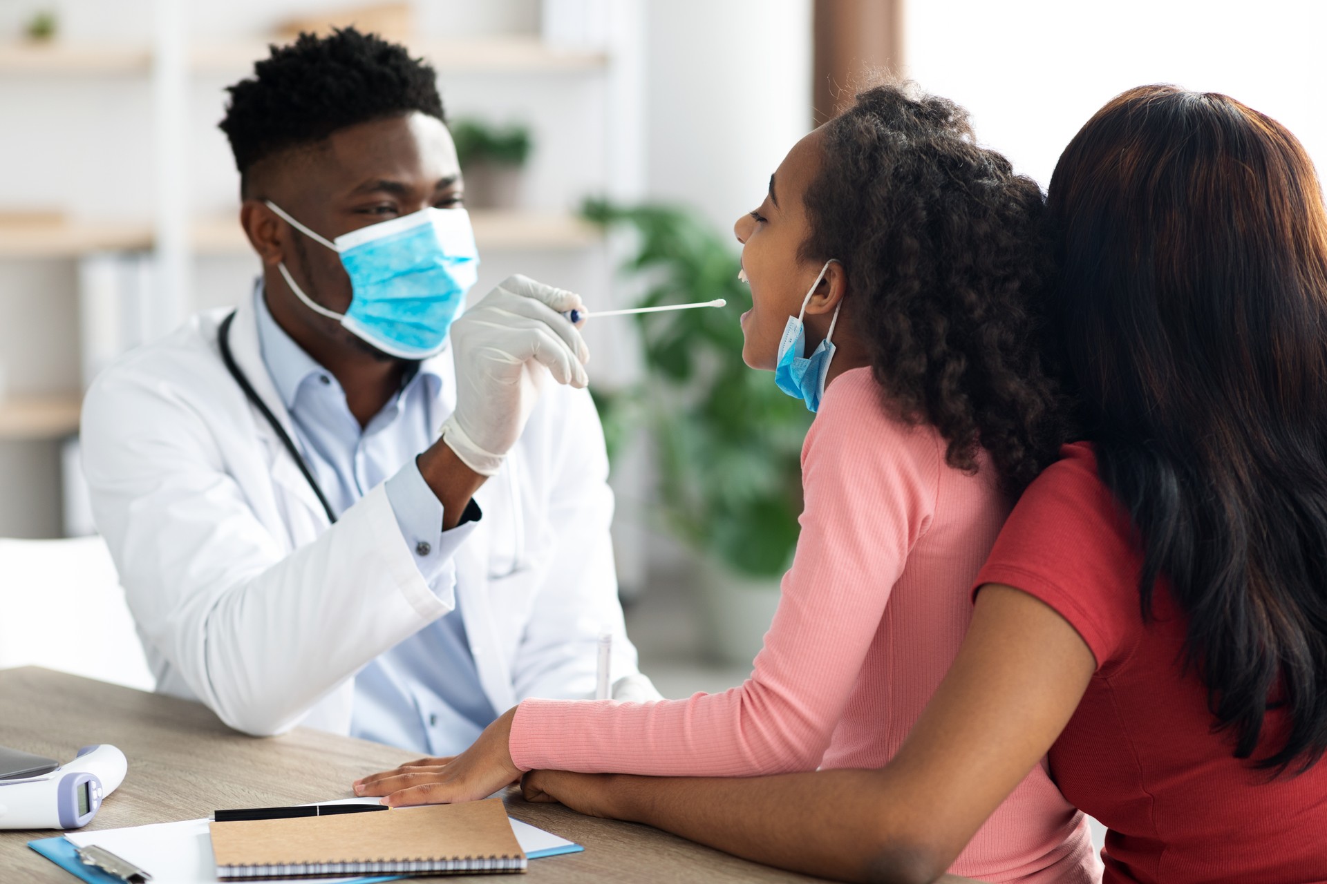 African american doctor taking oral swab test for little girl